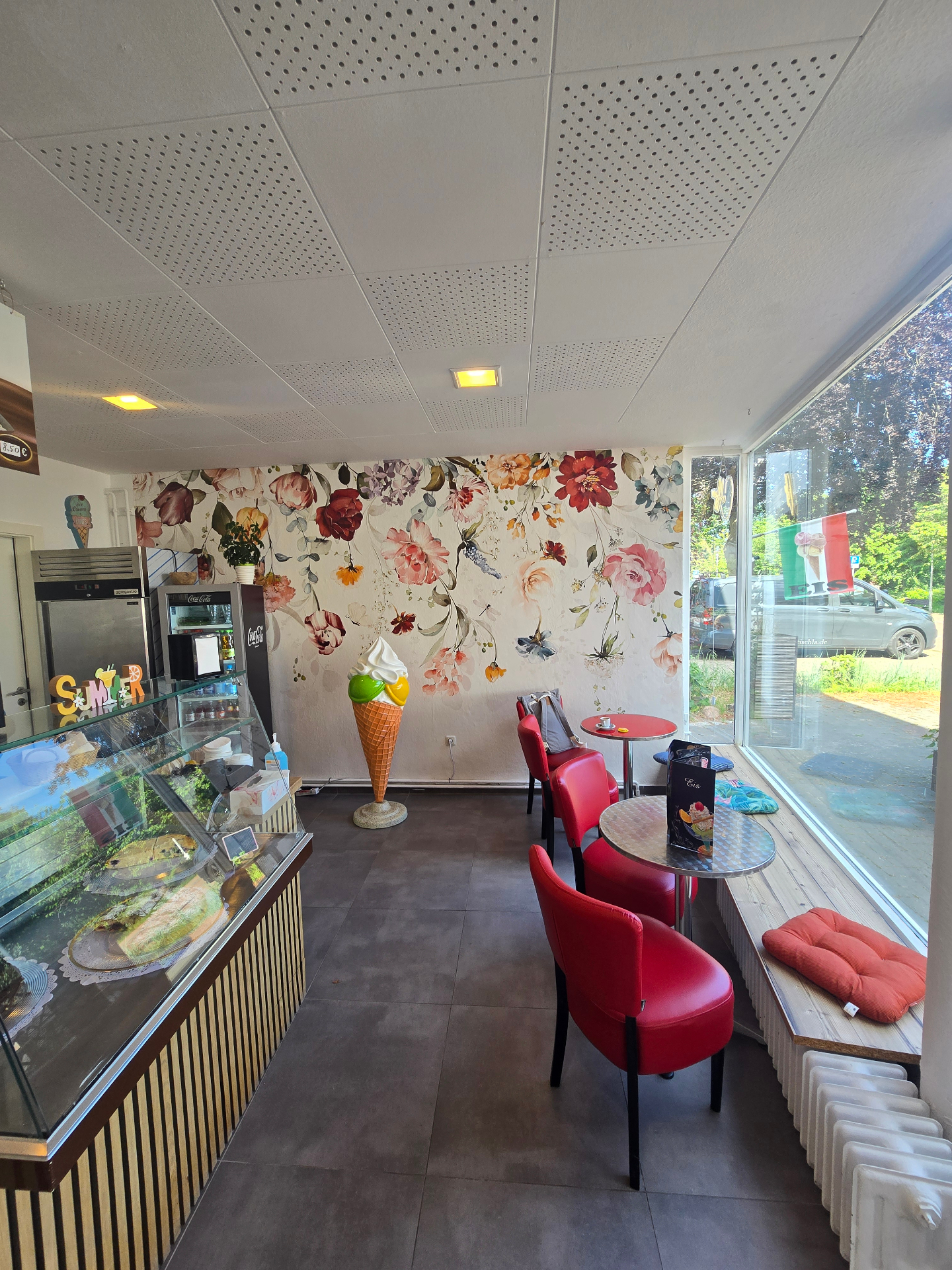 kugel & kruste – Innenraum mit floraler Wand und Eisvitrine